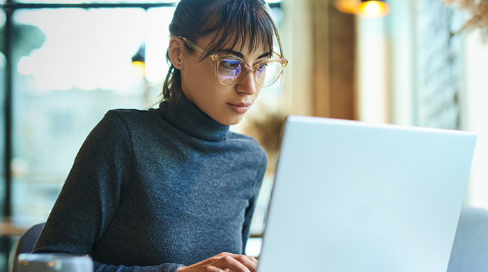 Woman with glasses working on laptop. 