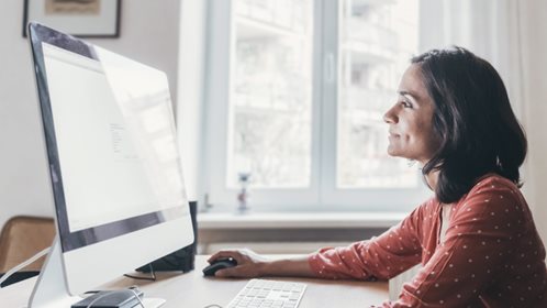 Woman in a sunny room looking at a computer screen.